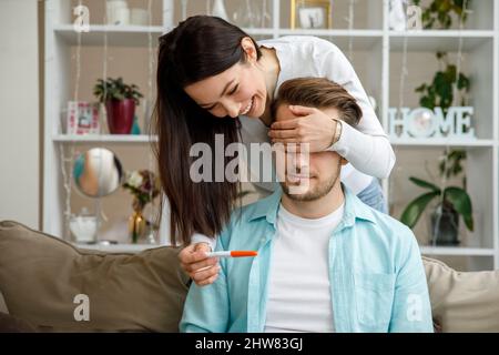 Donna che sorprende suo marito con test di gravidanza positivo, Foto Stock