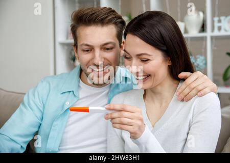 Donna che sorprende suo marito con test di gravidanza positivo, Foto Stock