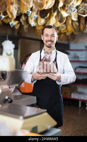 Assistente maschile positivo che mostra un pezzo di carne Foto Stock