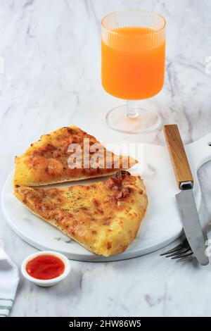 Pizza Cheesy a due fette con un bicchiere di succo d'arancia, sul tavolo bianco Foto Stock