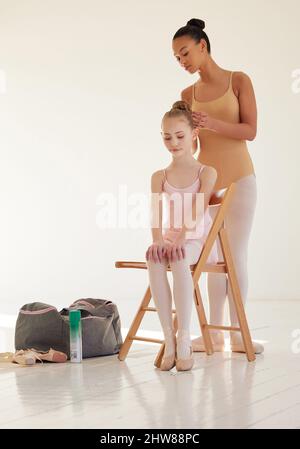 Il successo è il luogo in cui si incontrano preparazione e opportunità. Scatto di una ballerina che aiuta una ragazza più giovane a danzare i capelli in uno studio di danza. Foto Stock