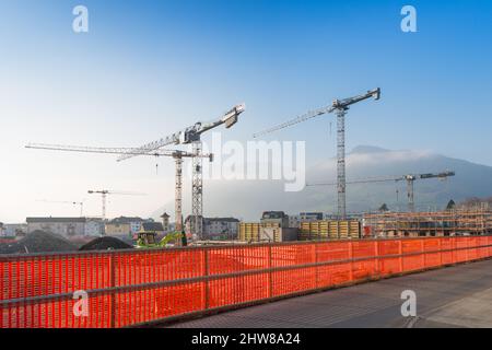 Sulla costruzione di case diverse gru. Barriera di sicurezza intorno alla costruzione dell'edificio. Foto Stock