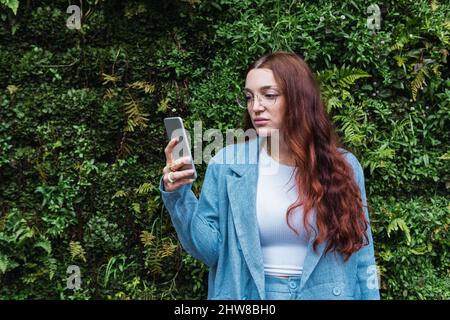 Una giovane donna d'affari seria che guarda il suo smartphone. Primo piano di mani di una ragazza che scrive un messaggio in un telefono cellulare, spazio vuoto per il testo Foto Stock