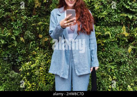 Bella giovane donna d'affari che guarda il suo smartphone. Primo piano di mani di una ragazza che scrive un messaggio in un telefono cellulare, spazio vuoto per il testo Foto Stock