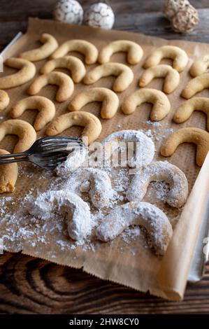 I tradizionali biscotti di natale tedeschi, chiamati 'vanillekipferl' freschi cotti e serviti su un foglio da forno rivestito di zucchero in polvere. Foto Stock