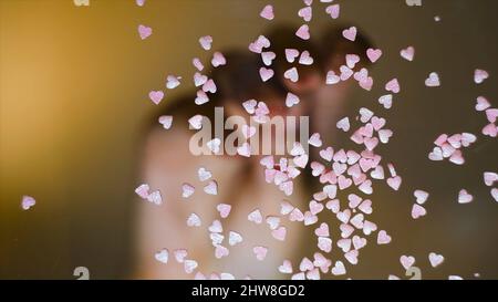 Primo piano di spruzzare a forma di cuori. Concetto. Vista dal basso di vetro trasparente con spolverini multicolore sparsi su di esso. Spruzzata multicolore Foto Stock