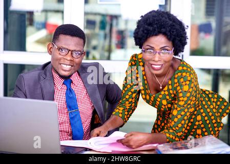 uomo d'affari e donna d'affari che lavorano insieme al computer in ufficio e guardano la fotocamera sorridendo. Foto Stock