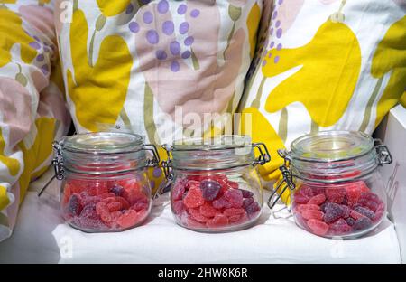 Cuori di marmellata in vasetti di vetro sullo sfondo di cuscini luminosi. Foto Stock
