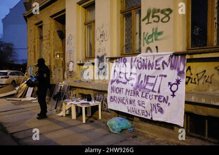 Lipsia, Germania. 04th Mar 2022. Un poliziotto si trova di fronte ad un edificio di appartamenti nella parte est della città con una bandiera su di esso. Nel pomeriggio, gli attivisti di sinistra occupavano l'edificio vuoto. La polizia ha poi ripulito l'edificio. Credit: dpa/dpa-Zentralbild/dpa/Alamy Live News Foto Stock