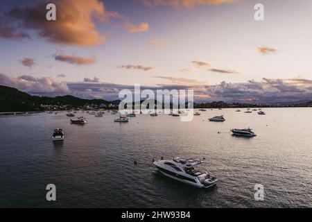 Molti yacht ormeggiati al largo della costa al tramonto. Foto Stock