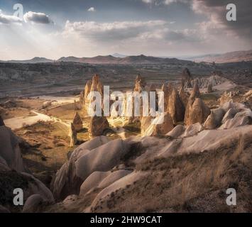Valli della Cappadocia con pittoresche scogliere e montagne in Turchia al tramonto Foto Stock