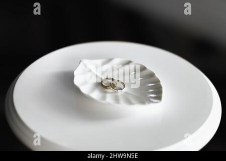 Anelli di nozze su un basamento bianco nella forma di una foglia Foto Stock