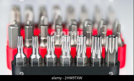 Primo piano di kit di cacciaviti in metallo Torx, esagonali o pozidriv su sfondo bianco sfocato. Set di punte a stella in acciaio e kit di cacciaviti di varie dimensioni. Foto Stock