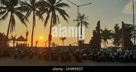 Vista panoramica delle sagome di molti motocicli parcheggiati e palme al tramonto Foto Stock