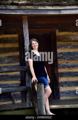 La giovane donna ama visitare la cabina di sosta del pullman sulla piazza di Collierville, Tennessee. È appoggiata contro la ringhiera sul portico anteriore un Foto Stock