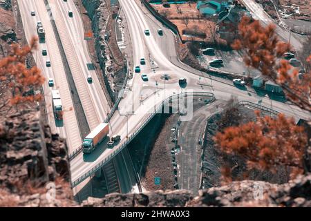 Autostrada europea Route E18 tra Oslo e Kristiansand. Auto di passaggio. Vista dalla roccia sopra la strada, primo piano sfocato. Foto Stock