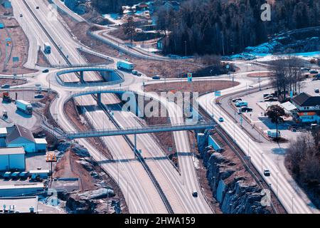 Autostrada europea Route E18 tra Oslo e Kristiansand. Auto di passaggio. Vista dalla roccia sopra la strada, primo piano sfocato. Foto Stock