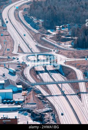 Autostrada europea Route E18 tra Oslo e Kristiansand. Auto di passaggio. Vista dalla roccia sopra la strada, primo piano sfocato. Foto Stock