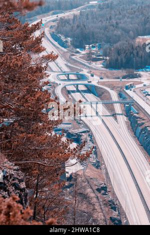 Autostrada europea Route E18 tra Oslo e Kristiansand. Auto di passaggio. Vista dalla roccia sopra la strada, primo piano sfocato. Foto Stock