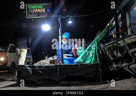 Un venditore di strada che usa una lampada solare mentre fornisce i servizi ai suoi clienti giù dalle strade in baraccopoli di Kibera.in baraccopoli di Kibera, la maggior parte dei residenti specialmente i fornitori di strada, scuole private, organizzazioni non governative, luci di strada, e tutte le scuole utilizzano il sistema di energia solare a basso costo, che è una fonte di energia più affidabile ed economica. Ciò ha reso più facile il riciclaggio della maggior parte dell'energia elettrica consumata dai residenti e ha anche contribuito a ridurre l'elevato numero di morti che si verificano a causa delle scosse elettriche e degli incendi di slum quotidiani. Foto Stock