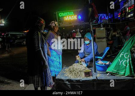 Un venditore di strada che usa una lampada solare mentre fornisce i servizi ai suoi clienti giù dalle strade in baraccopoli di Kibera.in baraccopoli di Kibera, la maggior parte dei residenti specialmente i fornitori di strada, scuole private, organizzazioni non governative, luci di strada, e tutte le scuole utilizzano il sistema di energia solare a basso costo, che è una fonte di energia più affidabile ed economica. Ciò ha reso più facile il riciclaggio della maggior parte dell'energia elettrica consumata dai residenti e ha anche contribuito a ridurre l'elevato numero di morti che si verificano a causa delle scosse elettriche e degli incendi di slum quotidiani. Foto Stock