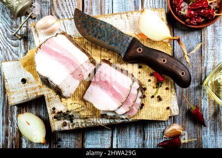 Pezzi di pancetta salata su sfondo scuro. Cibo sano con pranami spezie ed erbe. Salato grasso, lardo, sego, grasso Foto Stock