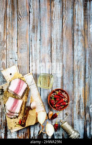 Pezzi di pancetta salata su sfondo scuro. Cibo sano con pranami spezie ed erbe. Salato grasso, lardo, sego, grasso Foto Stock