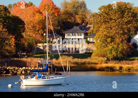 Una barca a vela è ormeggiata al largo della riva di un palazzo sul lungomare a Greenwich, Connecticut Foto Stock