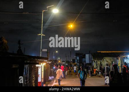 Nairobi, Kenya. 28th Feb 2022. Residenti locali tornare a casa passato la comunità solare alimentato luci di strada in Kibera slums.in Kibera slums, la maggior parte dei residenti in particolare i venditori di strada, scuole private, organizzazioni non governative, luci di strada, e le scuole sono tutti utilizzando il sistema di energia solare a basso costo che è una fonte più affidabile e a basso costo di energia. Ciò ha reso più facile il riciclaggio della maggior parte dell'energia elettrica consumata dai residenti e ha anche contribuito a ridurre l'elevato numero di morti che si verificano a causa delle scosse elettriche e degli incendi di slum quotidiani. (Credit Image: © Donwilso Foto Stock