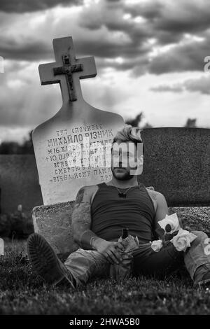 Uomo che guarda lontano di fronte ad una lapide Ucraina Foto Stock