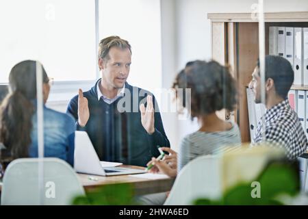 Spiegare le loro attività. Scatto ritagliato di quattro giovani designer che hanno un incontro d'affari. Foto Stock