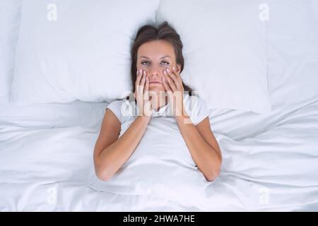 Donna addormentata con affaticamento cronico o depressione che si trova nel letto. Brutta mattina Foto Stock