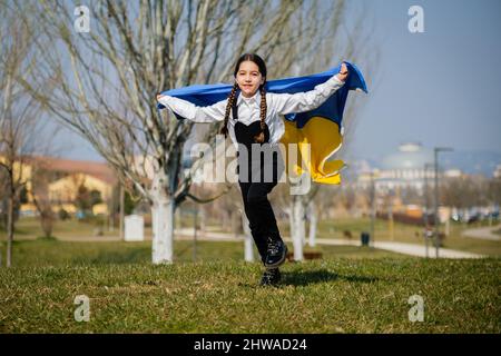 Felice ragazza Ucraina che corre al parco ondeggiare la bandiera nazionale gialla e blu. Concetto di amore per l'Ucraina. Indipendenza, bandiera, giorno della Costituzione Foto Stock