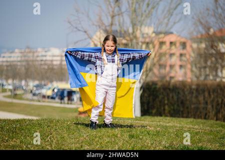 Felice ragazza Ucraina che corre al parco ondeggiare la bandiera nazionale gialla e blu. Concetto di amore per l'Ucraina. Indipendenza, bandiera, giorno della Costituzione Foto Stock