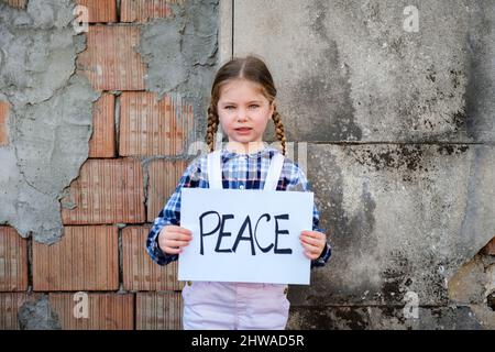 Bambina che tiene un poster con PACE scritta a sostegno della pace. Concetto di "nessuna guerra” in Ucraina e nel mondo. Conflitto russo Foto Stock