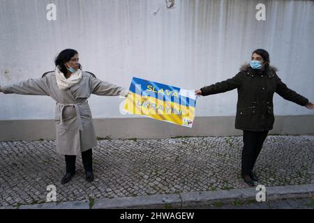 Lisbona, Portogallo. 04th Mar 2022. Due attivisti hanno un segno a sostegno del popolo ucraino durante un raduno contro l'invasione russa. L'evento è stato organizzato dall'Associazione degli ucraini in Portogallo di fronte all'ambasciata del governo cinese. Durante l'azione, sono stati visualizzati messaggi che chiedevano ai governi di opporsi fermamente all'aggressione contro l'Ucraina. Questa protesta mira anche a dimostrare la solidarietà della comunità portoghese e Ucraina che vive nel paese. Credit: SOPA Images Limited/Alamy Live News Foto Stock