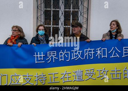 Lisbona, Portogallo. 04th Mar 2022. Gli attivisti tengono una bandiera a sostegno del popolo ucraino durante un raduno contro l'invasione russa. L'evento è stato organizzato dall'Associazione degli ucraini in Portogallo di fronte all'ambasciata del governo cinese. Durante l'azione, sono stati visualizzati messaggi che chiedevano ai governi di opporsi fermamente all'aggressione contro l'Ucraina. Questa protesta mira anche a dimostrare la solidarietà della comunità portoghese e Ucraina che vive nel paese. (Foto di Jorge Castellanos/SOPA Images/Sipa USA) Credit: Sipa USA/Alamy Live News Foto Stock