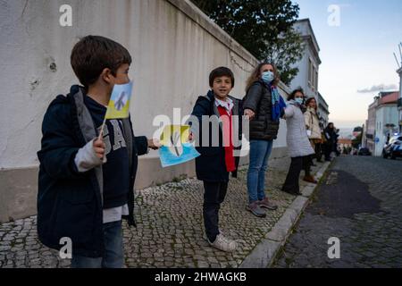 Lisbona, Portogallo. 04th Mar 2022. I bambini si vedono aggrapparsi le mani in solidarietà con il popolo ucraino durante un raduno contro l'invasione russa. L'evento è stato organizzato dall'Associazione degli ucraini in Portogallo di fronte all'ambasciata del governo cinese. Durante l'azione, sono stati visualizzati messaggi che chiedevano ai governi di opporsi fermamente all'aggressione contro l'Ucraina. Questa protesta mira anche a dimostrare la solidarietà della comunità portoghese e Ucraina che vive nel paese. (Foto di Jorge Castellanos/SOPA Images/Sipa USA) Credit: Sipa USA/Alamy Live News Foto Stock