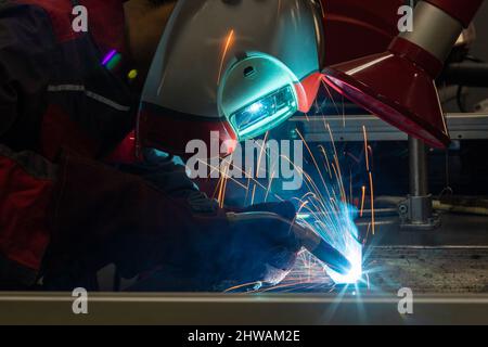 Una saldatrice che erige acciaio tecnico. Saldatrice industriale in acciaio in fabbrica tecnica. Foto Stock