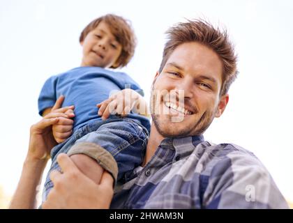 Ammalato portarlo alla grandezza. Ritratto di un giovane padre che porta il figlio sulle spalle. Foto Stock