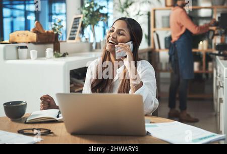 Sia il genere di persona che la gente ama lavorare con. Shot di una donna d'affari che parla sul suo cellulare mentre lavora da un bar. Foto Stock