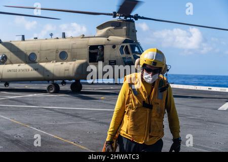 220218-N-VQ947-2052 OCEANO PACIFICO (DAL 18, 2022) — Aviation Boatswain’s Mate (Handler) 1st Classe Javier Munoz, di Chicago, rimuove un cuneo da un elicottero da trasporto medio Army CH-47F Chinook attaccato alla brigata dell'Aviazione da combattimento del 25th sul ponte di volo del molo di trasporto anfibio di classe San Antonio USS Portland (LPD 27), 18 febbraio 2022. Marinai e marines dell'Essex Amphibious Ready Group (ARG) e della Marine Expeditionary Unit (MEU) 11th stanno conducendo operazioni di routine nella flotta USA 3rd. (STATI UNITI Foto Navy di Mass Communication Specialist 2nd Classe Devin Kates) Foto Stock