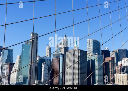 Vista dei grattacieli di Lower Manhattan attraverso i cavi del ponte di Brooklyn. Foto Stock