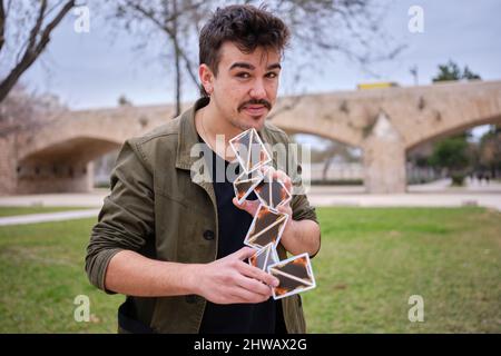 Mago di strada che fa un castello di scheda nell'aria mentre esegue un trucco Foto Stock