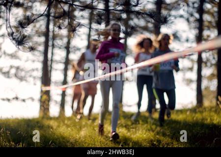 Foto sfocata di un gruppo di atleti che corre attraverso la foresta. Maratona nella foresta. Sport, corsa, concetto di maratona. Foto Stock