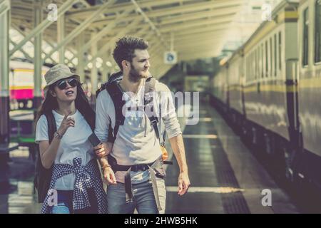 I viaggiatori multietnici stanno camminando e trovando il treno alla stazione ferroviaria, concetto di viaggio e trasporto Foto Stock