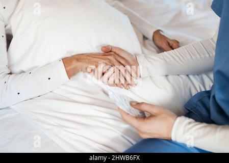 Date a qualcuno la vostra mano e date loro la speranza. Scatto corto di un'infermiera che tiene le mani con una donna anziana. Foto Stock