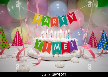 Torta di compleanno con candele bruciate con palloncini sullo sfondo. Torta di compleanno con candele per feste. Foto Stock
