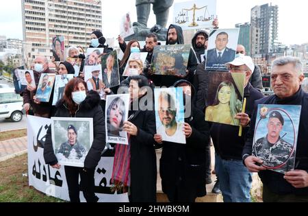 Beirut, Libano. 04th Mar 2022. Le famiglie delle vittime dell'esplosione si riuniscono nella statua dell'emigrante fuori dal porto per celebrare il 19th mese dell'esplosione, Beirut, Libano, marzo 4 2022. Le famiglie protestano contro i funzionari che stanno ostacolando le indagini sui porti, gestite dal giudice Tareq Bitar. Denunciano anche la volontà del governo di demolire i silos di grano devastati, che significa, nelle loro parole, "uccidere la memoria” del disastro. I manifestanti mostrano ritratti dei loro cari e tengono una bandiera che chiede “la rimozione degli ostacoli all’indagine e il rapido arresto dei criminali” Foto Stock