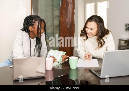 Donne multirazziali che lavorano insieme da casa Foto Stock